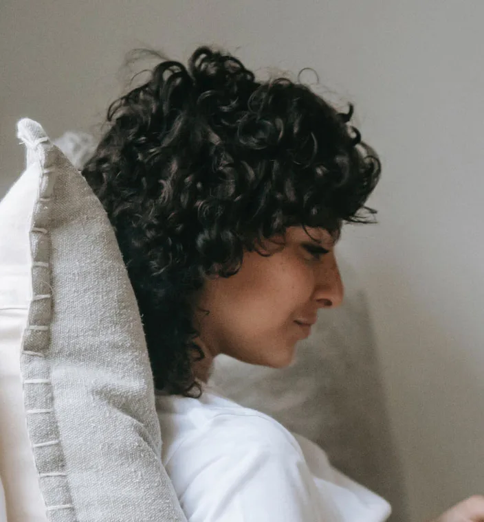 Side view of a woman sitting and resting her head on a pillow