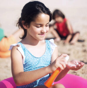 young girl applying sunscreen