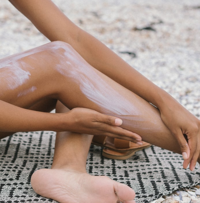 Closeup of a woman applying sunscreen on her legs