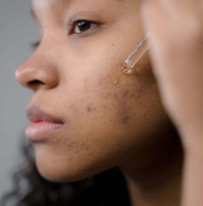 Closeup of African American woman applying serum to her face