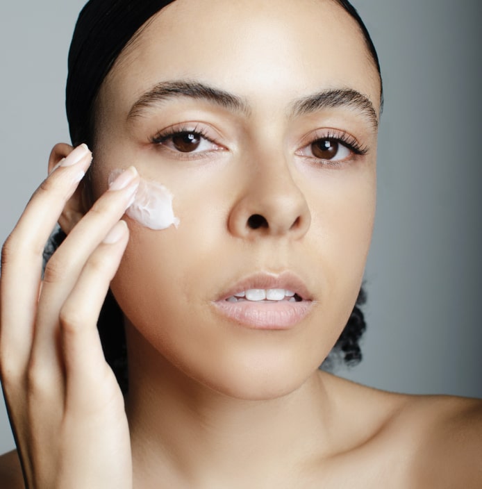 Closeup of a woman's face applying face cream