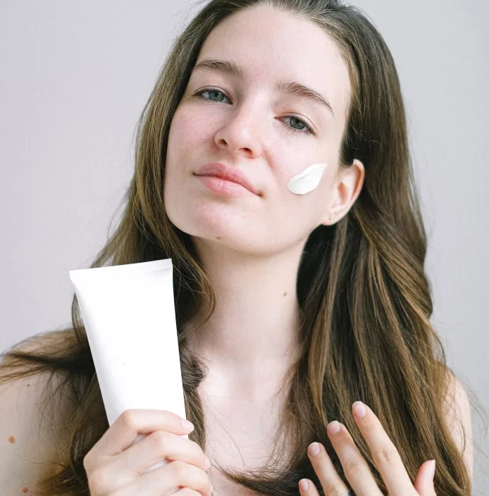 Young woman holding face cream