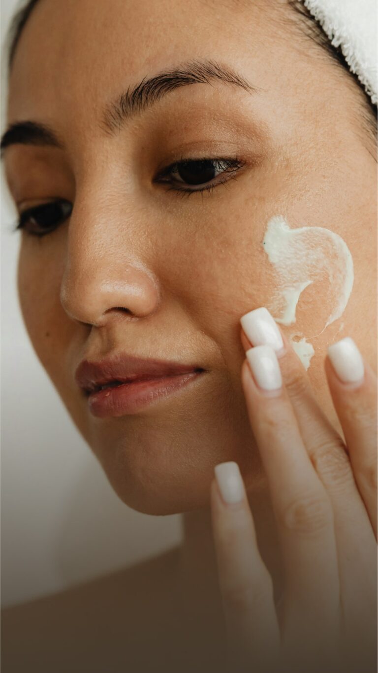 A woman applying cream to her face